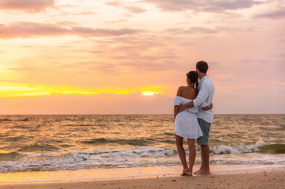 Couple Standing on Beach and Watching the Sunset